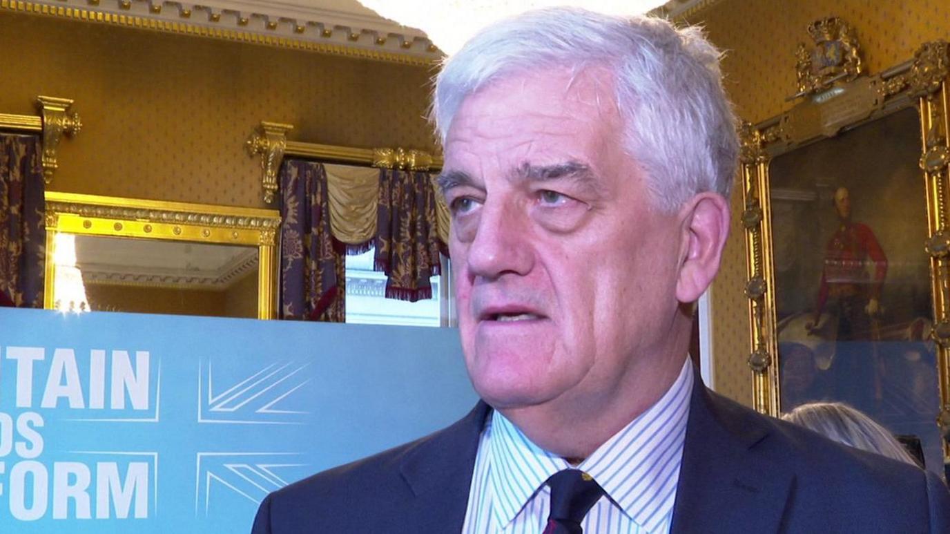 Chris Parry standing in front of a Reform UK banner