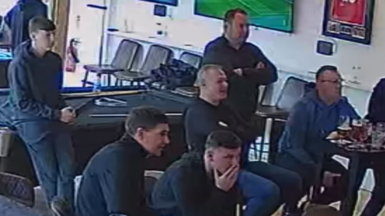 Group of men captured on CCTV watching football, with Steven Gerrard.