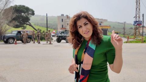 Correspondent Carine Torbey while Lebanese soldiers seen in the background in border town