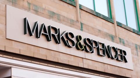 A sign above the entrance to a Marks and Spencer shop reading "MARKS & SPENCER" in capital letters.