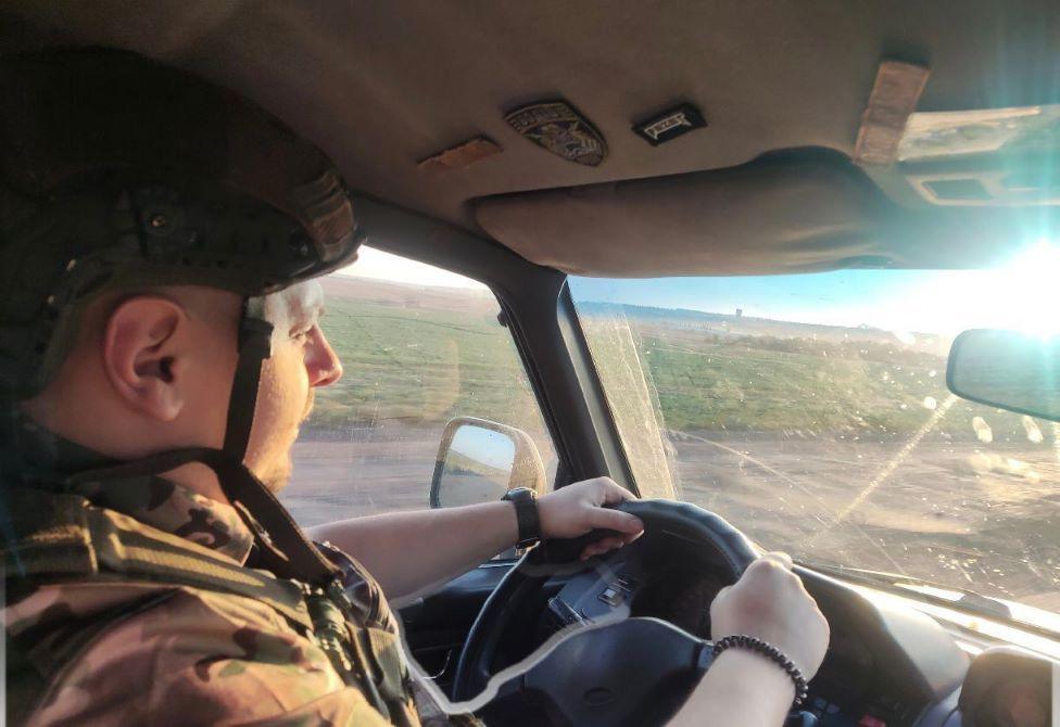 A man, in military uniform, drives a car