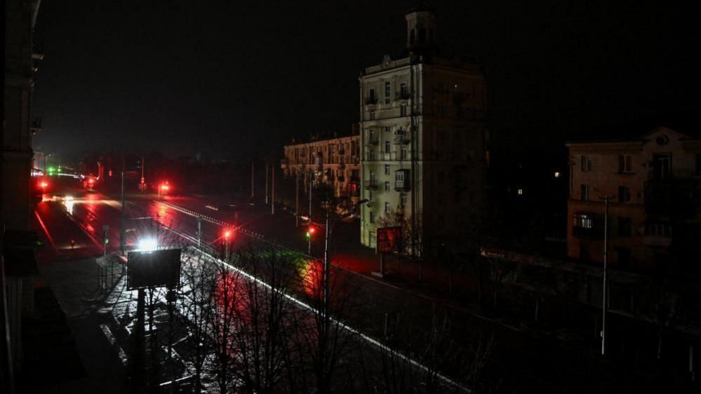 Cars move along a dark street during a power blackout after critical civil infrastructure was hit by today's Russian drone strikes.
