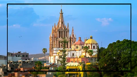 The Parroquia de San Miguel Arcu00e1ngel, a gothic church in San Miguel de Allende in Mexico, is shown against the evening sky. Its signature pink fau00e7ade and spires can be seen as well as its two domes (Credit: Getty Images)